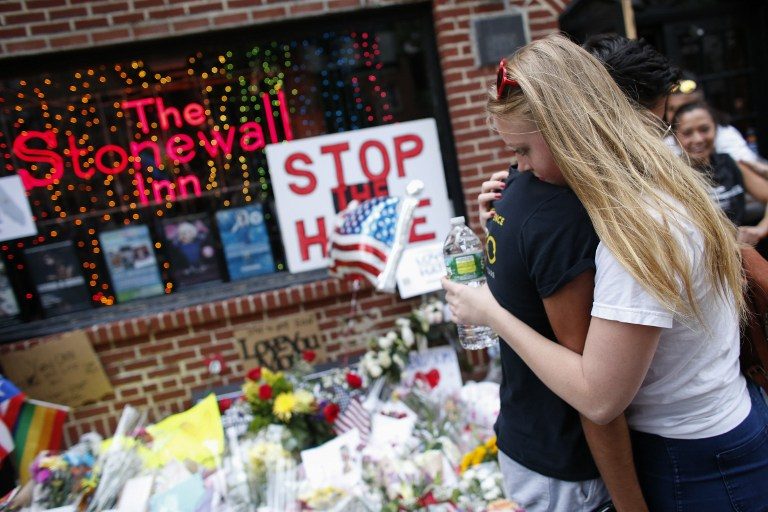 'STOP THE HATE'. A man and a woman embrace each other as they stand next to a memorial created in solidarity at Manhattan's historic Stonewall Inn to express their support for the victims killed at Pulse nightclub, June 13, 2016. Photo by Kena Betancur/AFP 