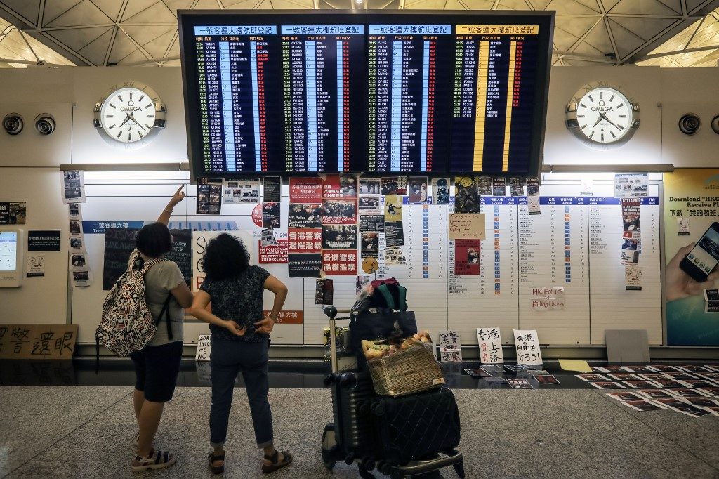 CANCELED FLIGHTS. Stranded passengers look at a flight information board after all flights were canceled at Hong Kong's international airport following a protest against the police brutality and the controversial extradition bill on August 12, 2019. Photo by Vivek Prakash/AFP 