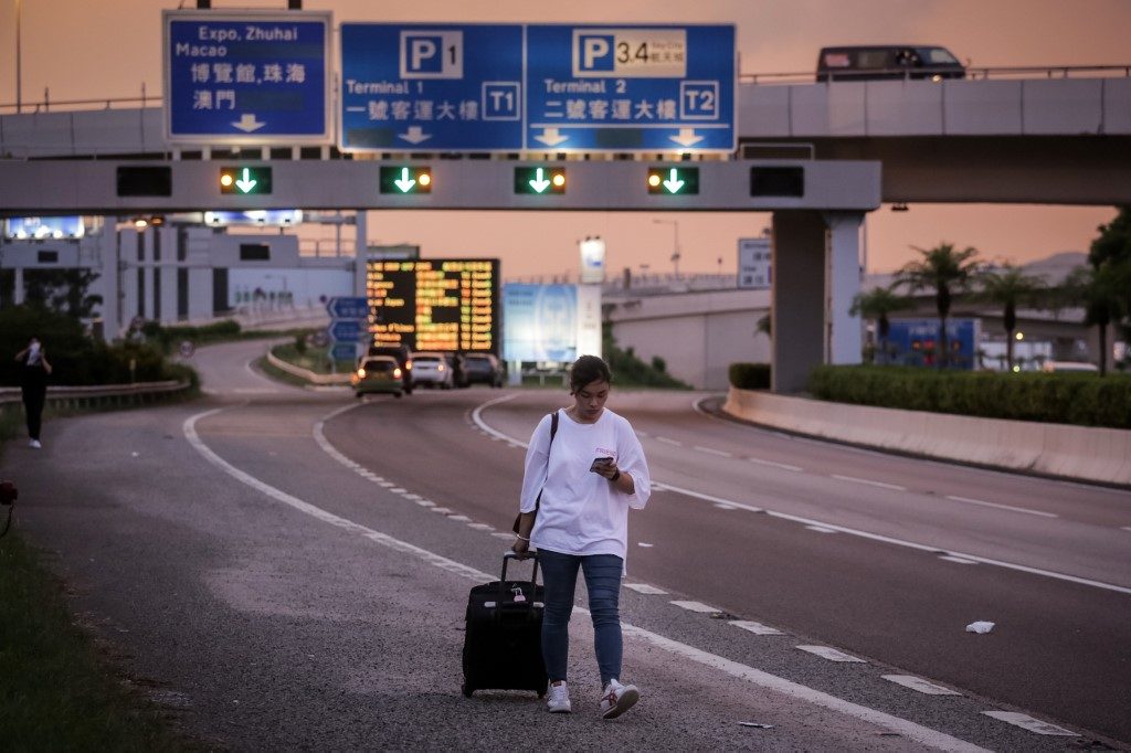 AFFECTED. A stranded passenger wheels her luggage along on a highway near Hong Kong's international airport following a protest against the police brutality and the controversial extradition bill on August 12, 2019. Photo by Vivek Prakash/AFP 