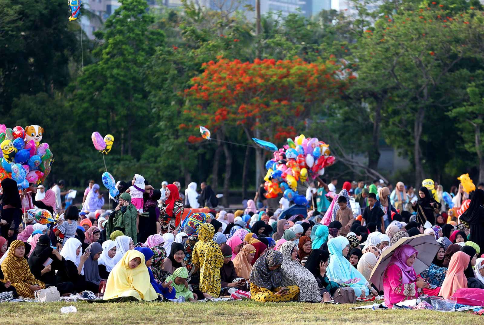 CELEBRATION. Muslim women of Marawi City give each other a hug after the Eid prayers (above) while families spend the rest of the morning at the Luneta Park in Manila. Photos by Martin San Diego and Inoue Jaena/Rappler   
