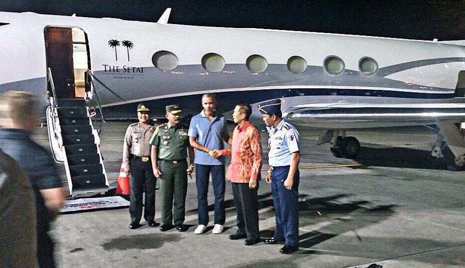 TIBA DI INDONESIA. Mantan Presiden Barack Obama mengenakan kaos, celana jeans dan sepatu sneakers menyalami Gubernur Bali Made Mangku Pastika ketika tiba di Bandara Ngurah Rai pada Jumat malam, 23 Juni. Foto diambil dari akun @shafigh 