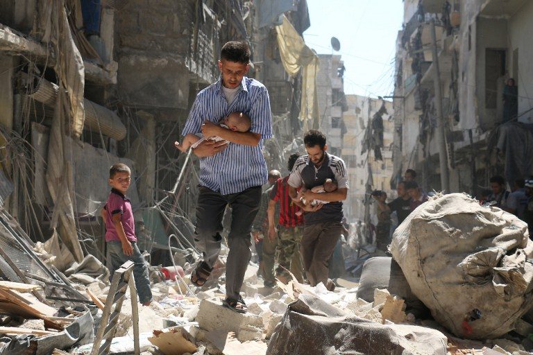 Syrian men carrying babies make their way through the rubble of destroyed buildings following a reported air strike on the rebel-held Salihin neighborhood of the northern city of Aleppo, on September 11, 2016. Ameer Alhalbi/AFP 