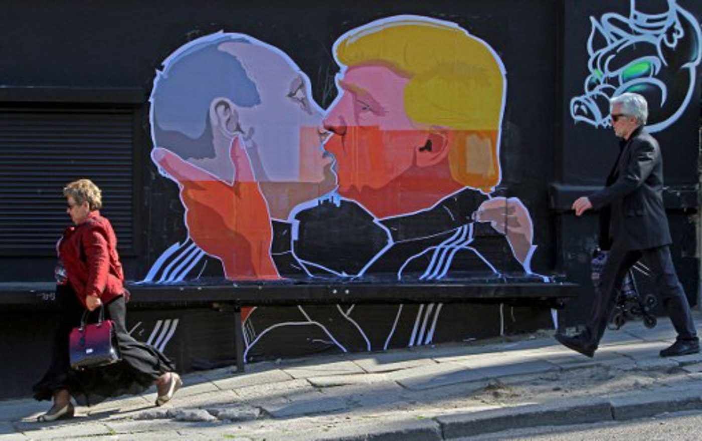 People walk past a mural on a restaurant wall depicting US Presidential hopeful Donald Trump and Russian President Vladimir Putin greeting each other with a kiss in the Lithuanian capital Vilnius on May 13, 2016. Petras Malukas/AFP 