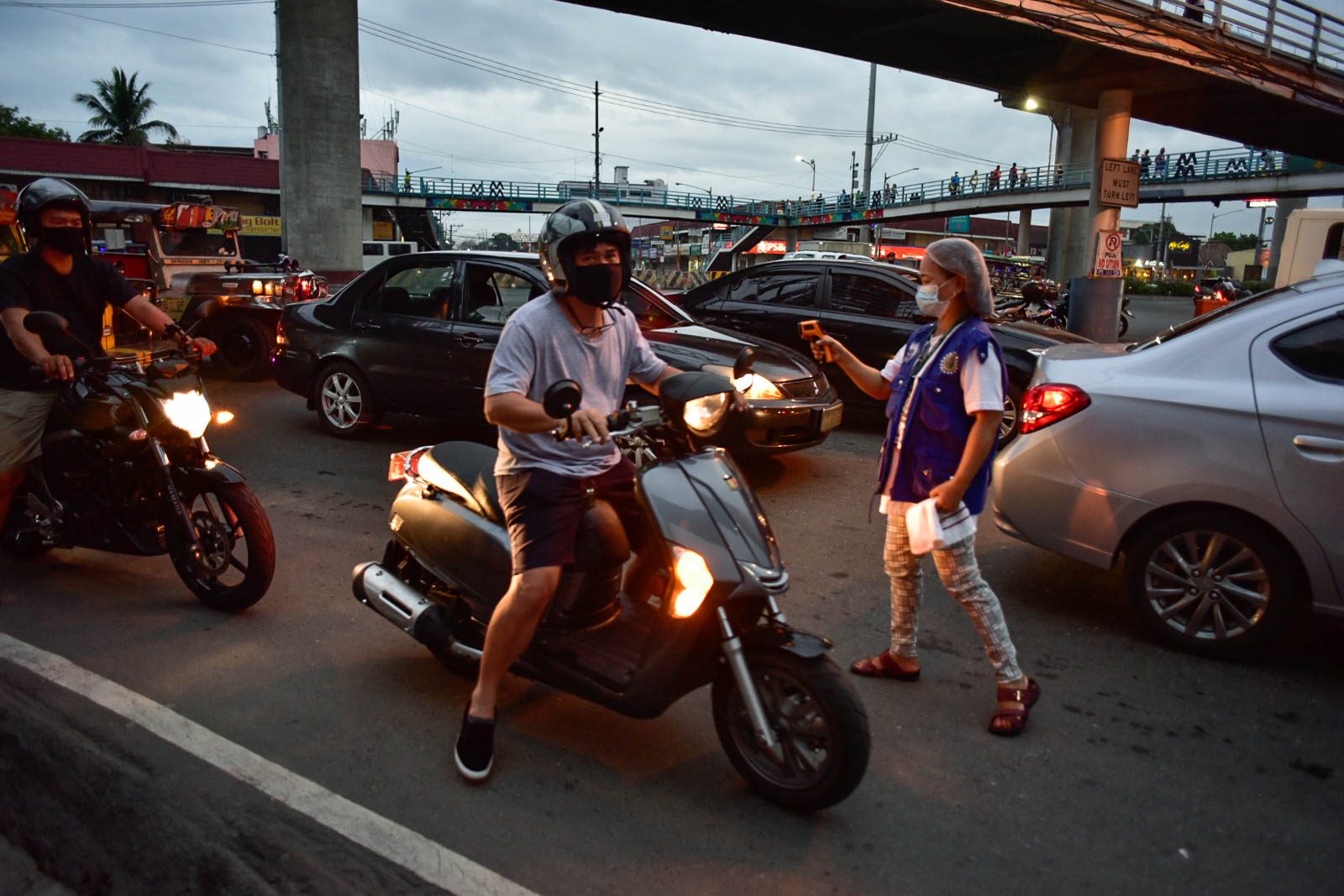 TEMPERATURE CHECK. Barangay health worker Jocelyn Landero checks the temperature of motorcycle riders along Marcos Highway on March 16, 2020. Photo by Rob Reyes/Rappler 