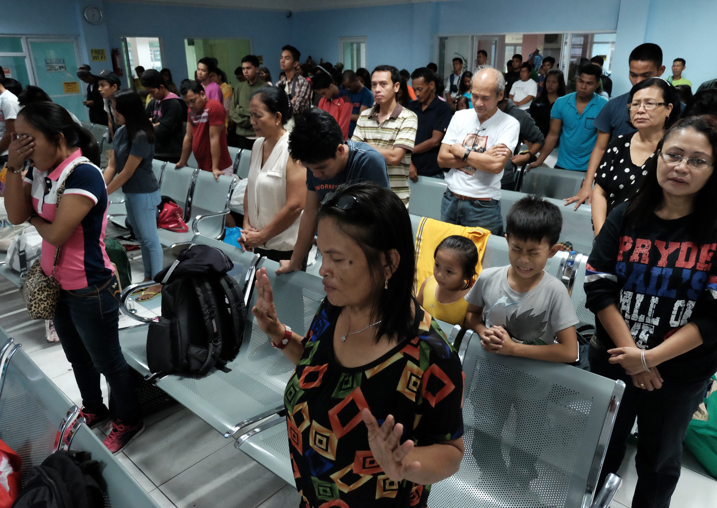 Stranded passengers offer prayers inside a port terminal in Tabaco, Albay on October 17, 2015. Photo by Zalrian Sayat/EPA 