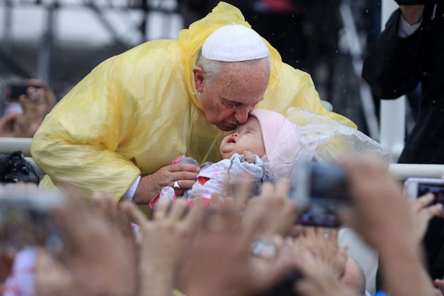 Pope Francis aboard his popemobile kisses a child prior to his mass at the Quirino grandstand in Manila on January 18, 2015. Photo by Zalrian Sayat/EPA