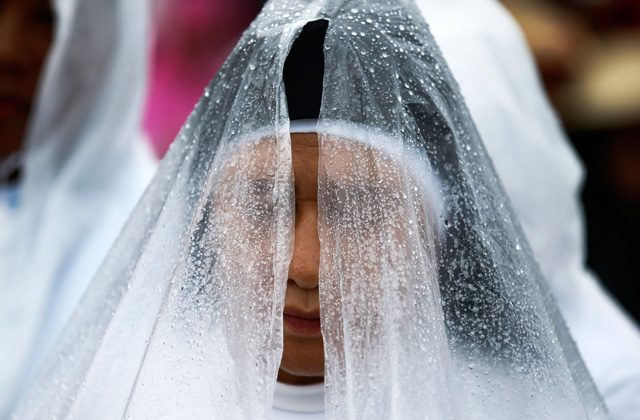 A nun prays during the downpour of heavy rains as Pope Francis celebrate a mass at the Quirino grandstand in Manila on January 18, 2015. Photo by Dennis Sabangan/EPA