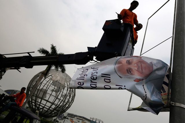 Workers rush to take down a billboard with the picture of Pope Francis amid a request from the Vatican to remove signages with images of the pontift in Manila, 14 January 2015. Photo by Francis Malasig/EPA
