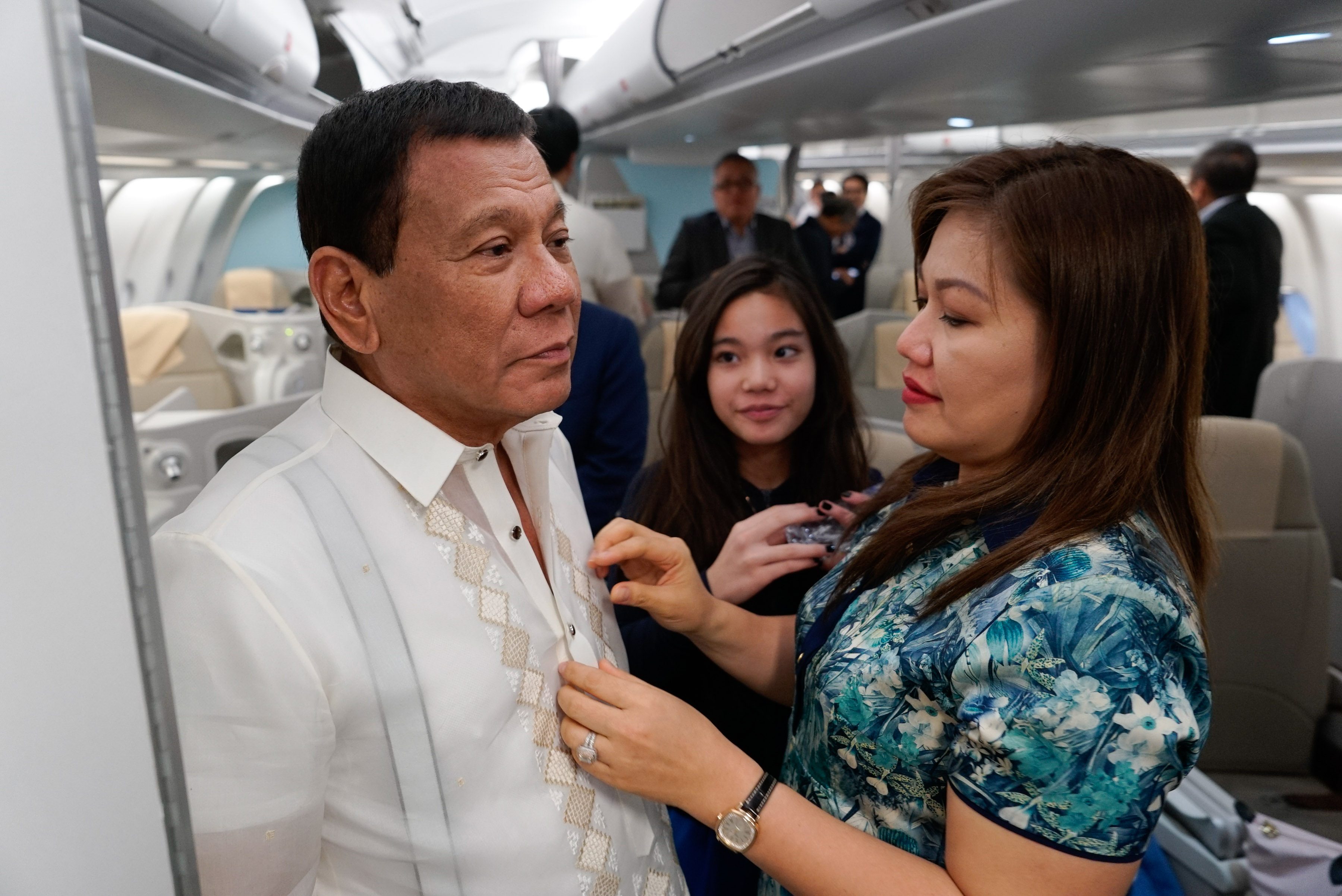 TRAVEL COMPANION. President Rodrigo Duterte gets his barong tagalog fixed by his partner Honeylet, with daughter Kitty looking on, before disembarking to start his Cambodia visit. Presidential photo 