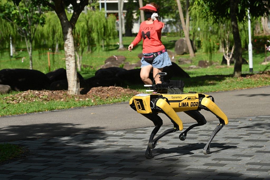 PARK PATROLLER. A woman jogs past a four-legged robot called Spot, which broadcasts a recorded message reminding people to observe safe distancing as a preventive measure against the spread of the COVID-19 novel coronavirus, during its two-week trial at the Bishan-Ang Moh Kio Park in Singapore on May 8, 2020. Photo by Roslan Rahman/AFP 