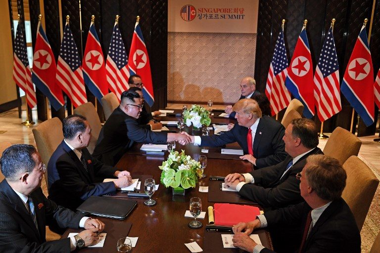 FIRST MEETING. US President Donald Trump (3rd R) shakes hands with North Korea's leader Kim Jong Un (3rd L) as they sit down with their respective delegations for the US-North Korea summit, at the Capella Hotel on Sentosa island in Singapore on June 12, 2018. Photo by Saul Loeb/AFP   