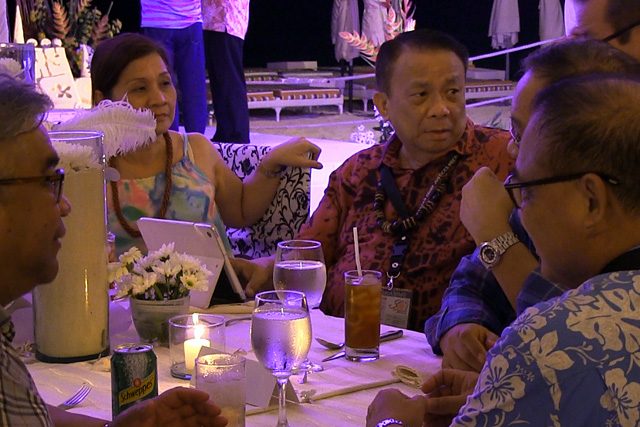 WORK. Philippine Associate Justice Lucas Bersamin, in his red Hawaiian shirt, works using a gadget at the 3rd ACJM opening dinner. Photo by Buena Bernal/Rappler    