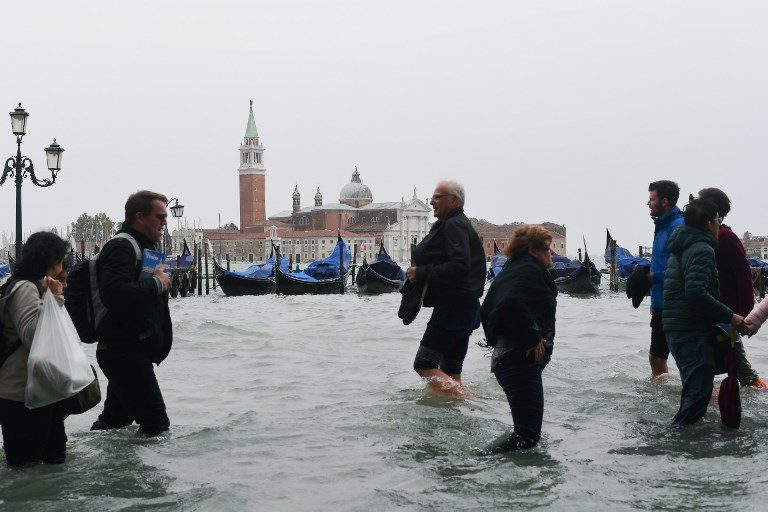 ACQUA ALTA. People walk in the flooded Riva degli Schiavoni in front of the San Giorgio church during a high-water alert in Venice on October 29, 2018. Photo by Miguel Medina/AFP  