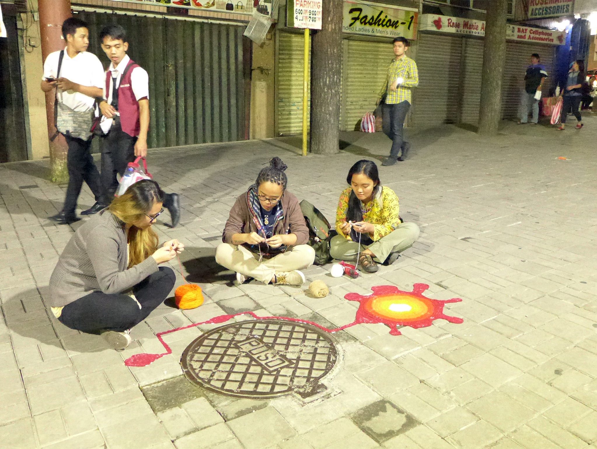 STREET ART. The yarnbombers knit their creations as passers-by watch. Photo by Mau Victa/Rappler   
