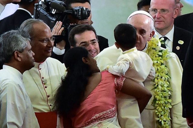 Pope Francis kisses a child as he arrives for an inter-religous meeting at Bandaranaike Memorial International Conference Hall in Colombo on January 13, 2015. Photo by Giuseppe Cacace/AFP