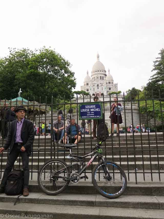 Man and his bicycle. Square Louise Michel. Montmartre. Sacre Couer in background 