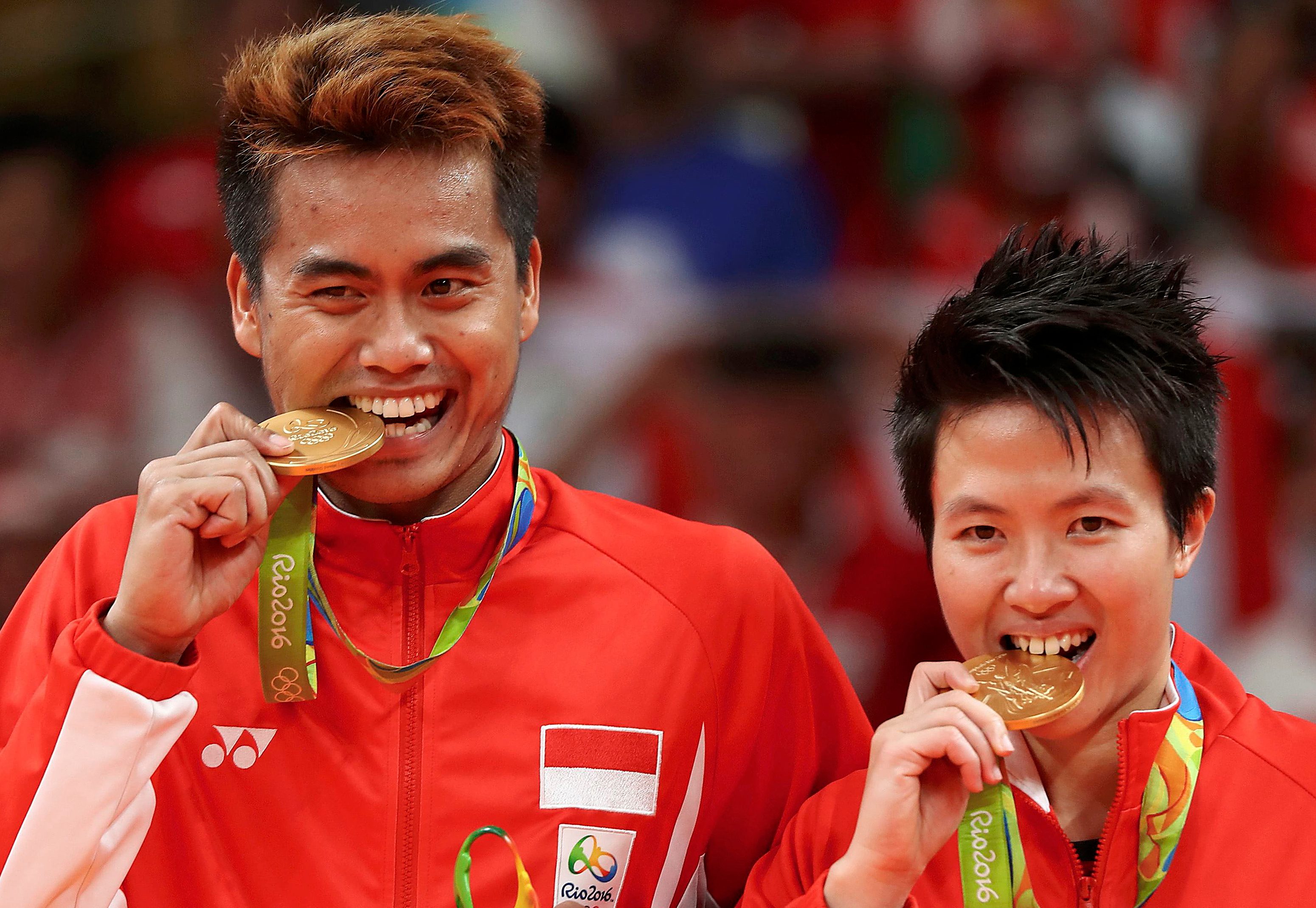 Pebulu tangkis Tontowi Ahmad (kiri) dan Liliyana Natsir menggigit medali emas usai mengalahkan pasangan Malaysia dalam partai final ganda campuran Olimpiade Rio 2016, pada 17 Agustus 2016. Foto oleh Mike Blake/Antara/Reuters 