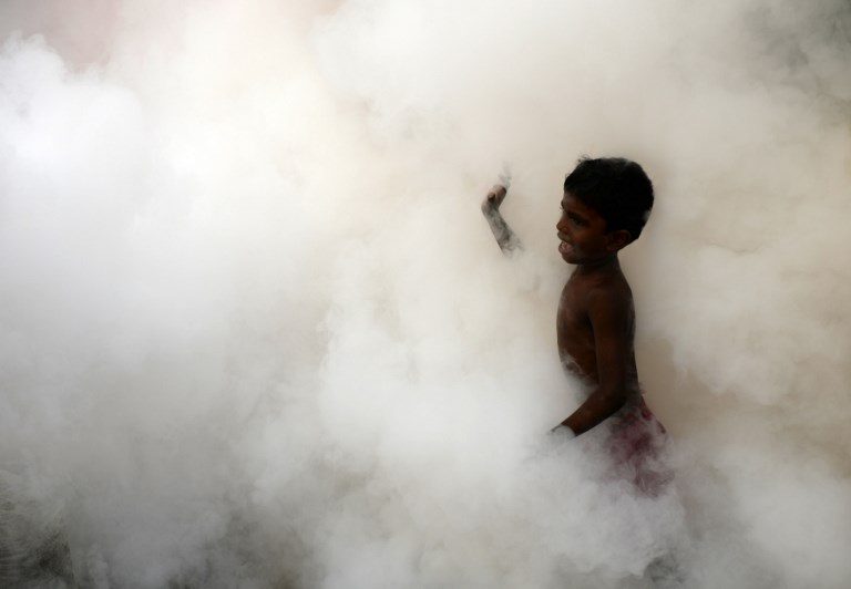 DENGUE PREVENTION. An Indian boy follows a municipal worker fumigating the area to prevent mosquitos from breeding in Chennai on October 7, 2017. Photo by Arun Sankar/AFP  