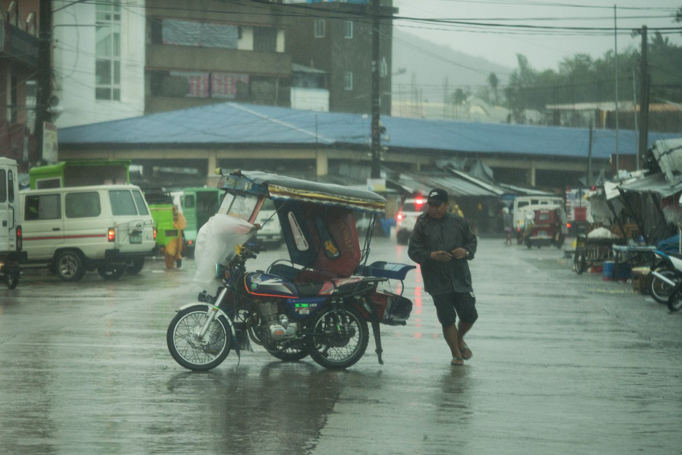 STRONG WINDS. A man runs for his tricycle as it is moved by strong winds in Tacloban City