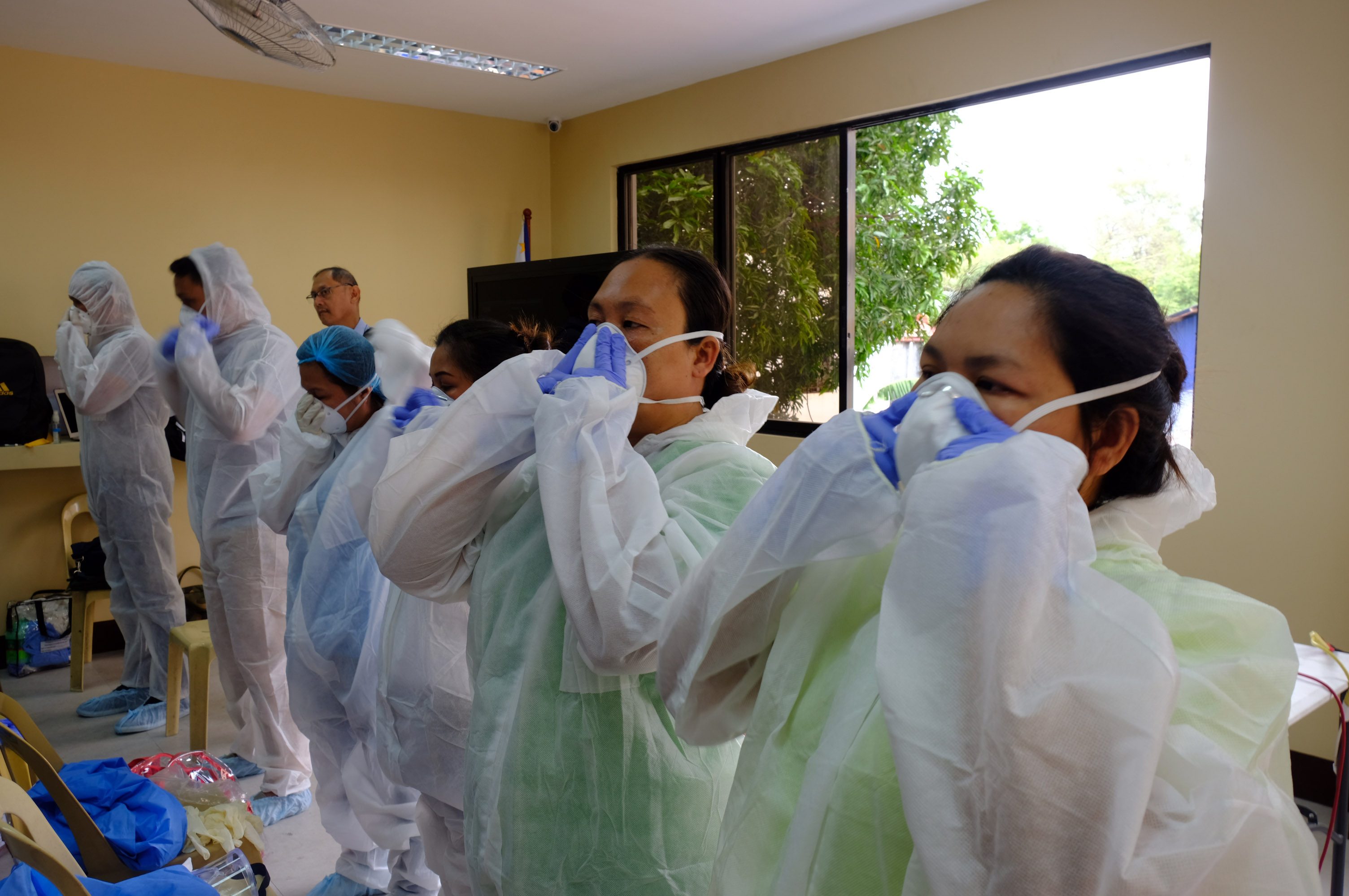 TRAINING SESSION. Local health workers in Quezon City are taught how to properly wear personal protective equipment before directly handling patients under investigation for COVID-19. Photo from Quezon City Disaster Risk Reduction and Management Office 