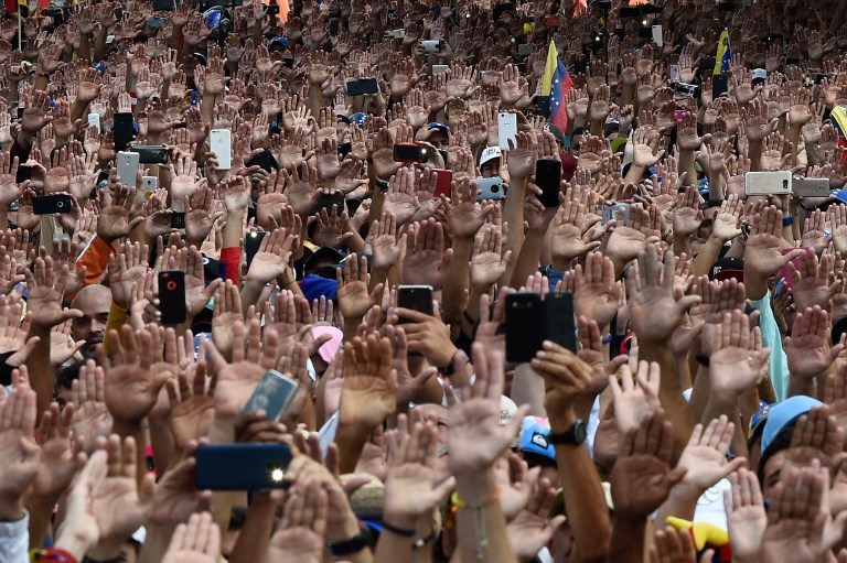 'ACTING PRESIDENT.' People raise their hands during a mass opposition rally against President Nicolas Maduro in which Venezuela's National Assembly head Juan Guaido (out of frame) declared himself the country's 'acting president,' on the anniversary of a 1958 uprising that overthrew a military dictatorship, in Caracas on January 23, 2019. File photo by Federico Parra/AFP  