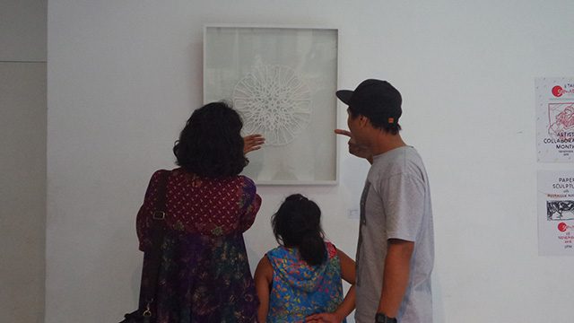 Wilman Hermana (kanan), pematung sekaligus pengelola dari SemAta Gallery, sedang menjelaskan karya Mujahidin Nurrahman kepada pengunjung. Foto oleh Tri Asrie Khalidya/Rappler. 