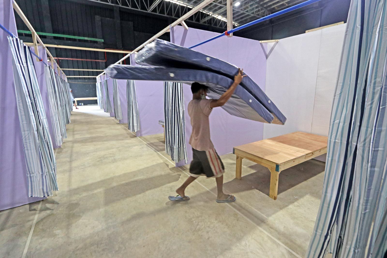 CONSTRUCTION IN A PANDEMIC. A worker carries mattresses during the construction of the back-up Barangay Isolation Center for coronavirus patients in Cebu City on May 27, 2020. Photo by Gelo Litonjua/Rappler 