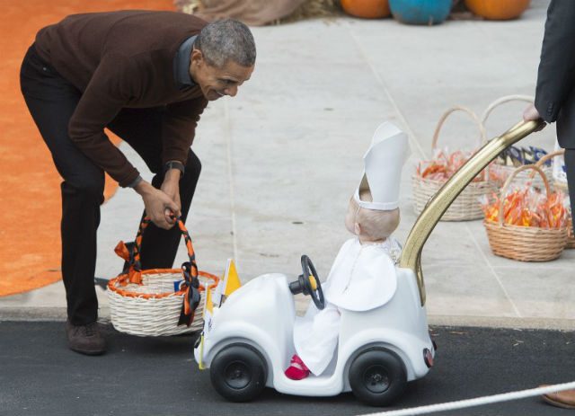 President Barack Obama greets a young child dressed as the Pope and riding in a "Popemobile" as he hands out treats to children trick-or-treating for Halloween on the South Lawn of the White House in Washington, DC on October 30 Photo by Saul Loeb/ AFP  