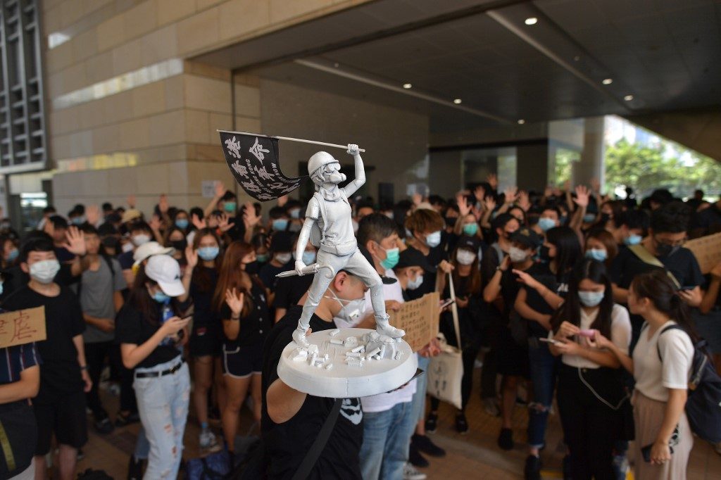 FREE HK. File photo of a man carrying a miniature statue as protesters and supporters gather outside the entrance to the West Kowloon Court in Hong Kong on October 2, 2019. Photo by Nicolas Asfouri/AFP 