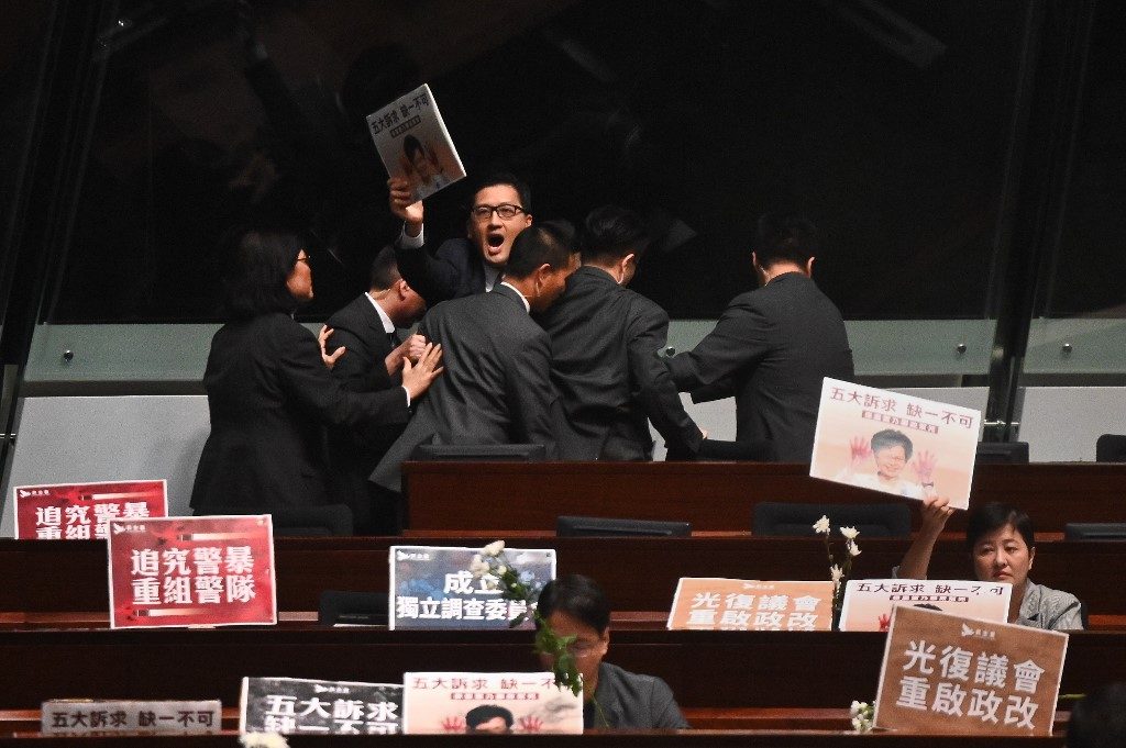 Hong Kong lawmakers dragged from chamber as leader heckled for second day