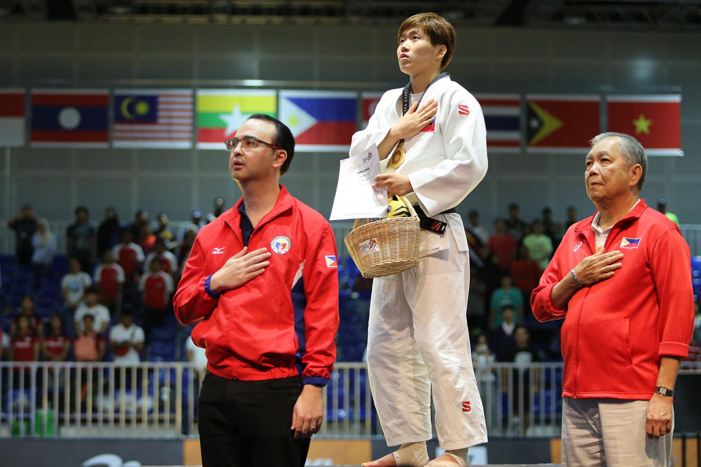 NATIONAL ANTHEM. Kiyomi Watanabe of the Philippines clinches the gold medal in the women's -63kg judo event. She is seen here during the Philippine national anthem with Philippine officials. Photo by PSC-POC Media Group 