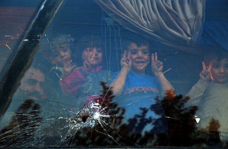 SEEKING REFUGE. Children peer through the window of a bus upon arriving at the Abu al-Zindeen checkpoint, near the northern Syrian town of al-Bab, after Jaish al-Islam fighters and their families from the former rebel bastion's main town of Douma were evacuated from the last rebel-held pocket in Eastern Ghouta on April 3, 2018. Photo by Nazeer al-Khatib/AFP   