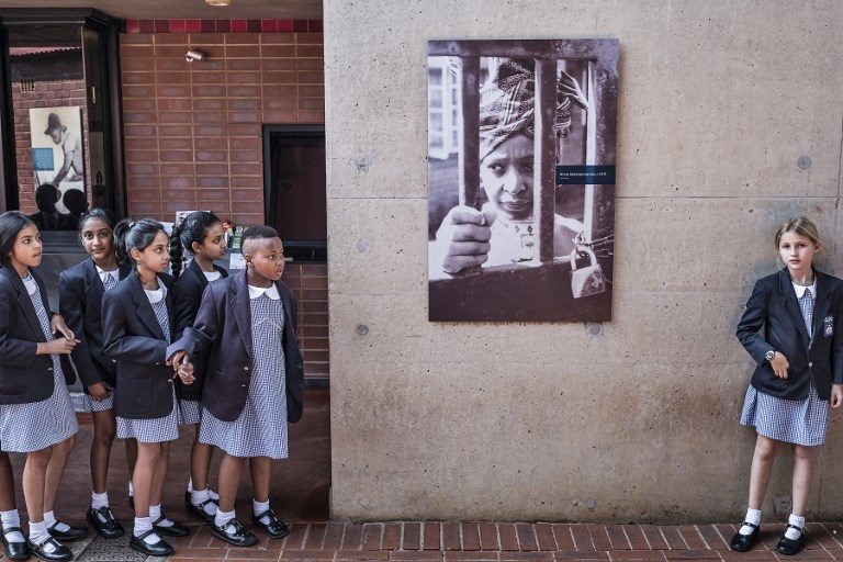 TRIBUTE. South African schoolchildren pause next to a portrait of the late South African anti-apartheid campaigner Winnie Madikizela-Mandela, ex-wife of African National Congress (ANC) leader Nelson Mandela, in her house on April 3, 2018, in Soweto. Photo by Marco Longari/AFP   