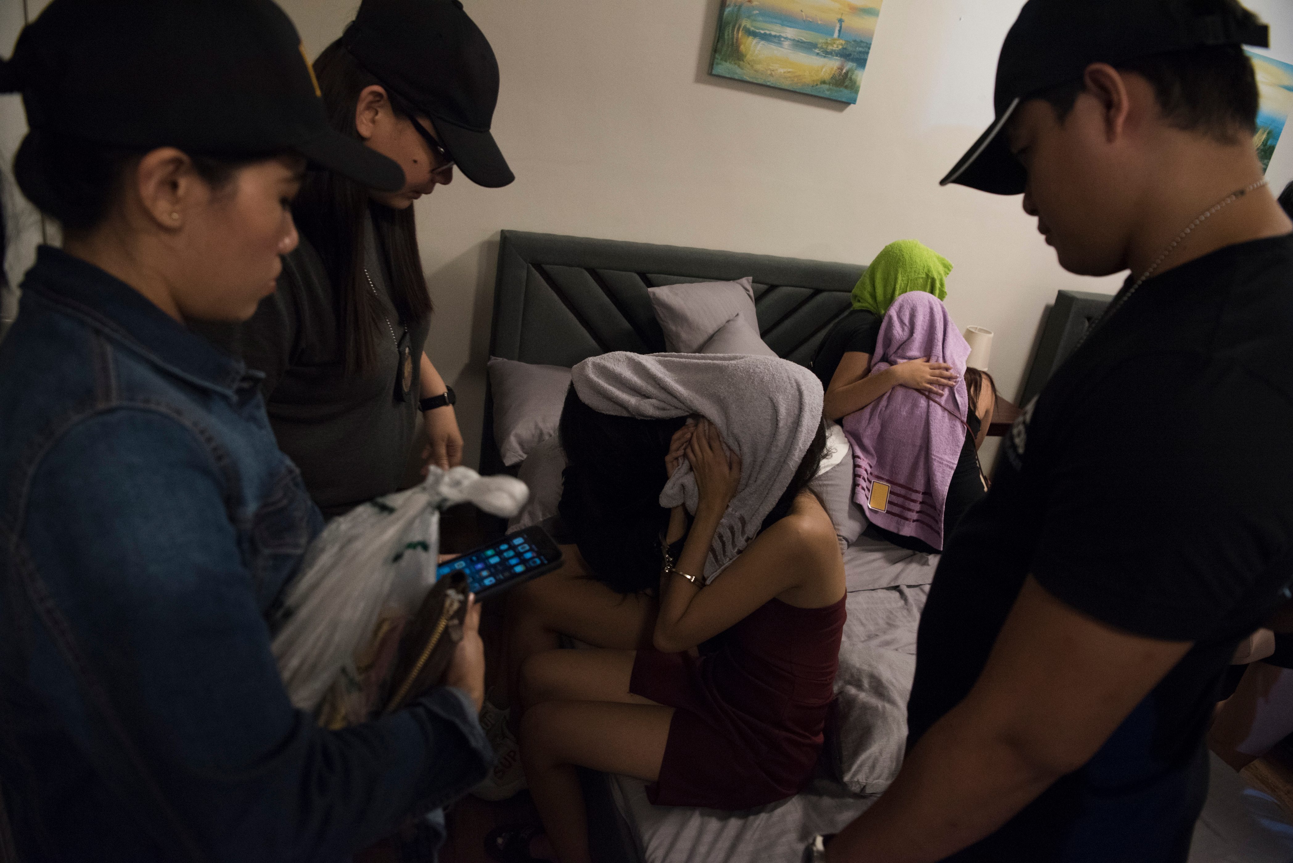 RESCUE. Police question two detained women while rescued victims comfort each other during a rescue operation in Marikina City on December 5, 2019.   