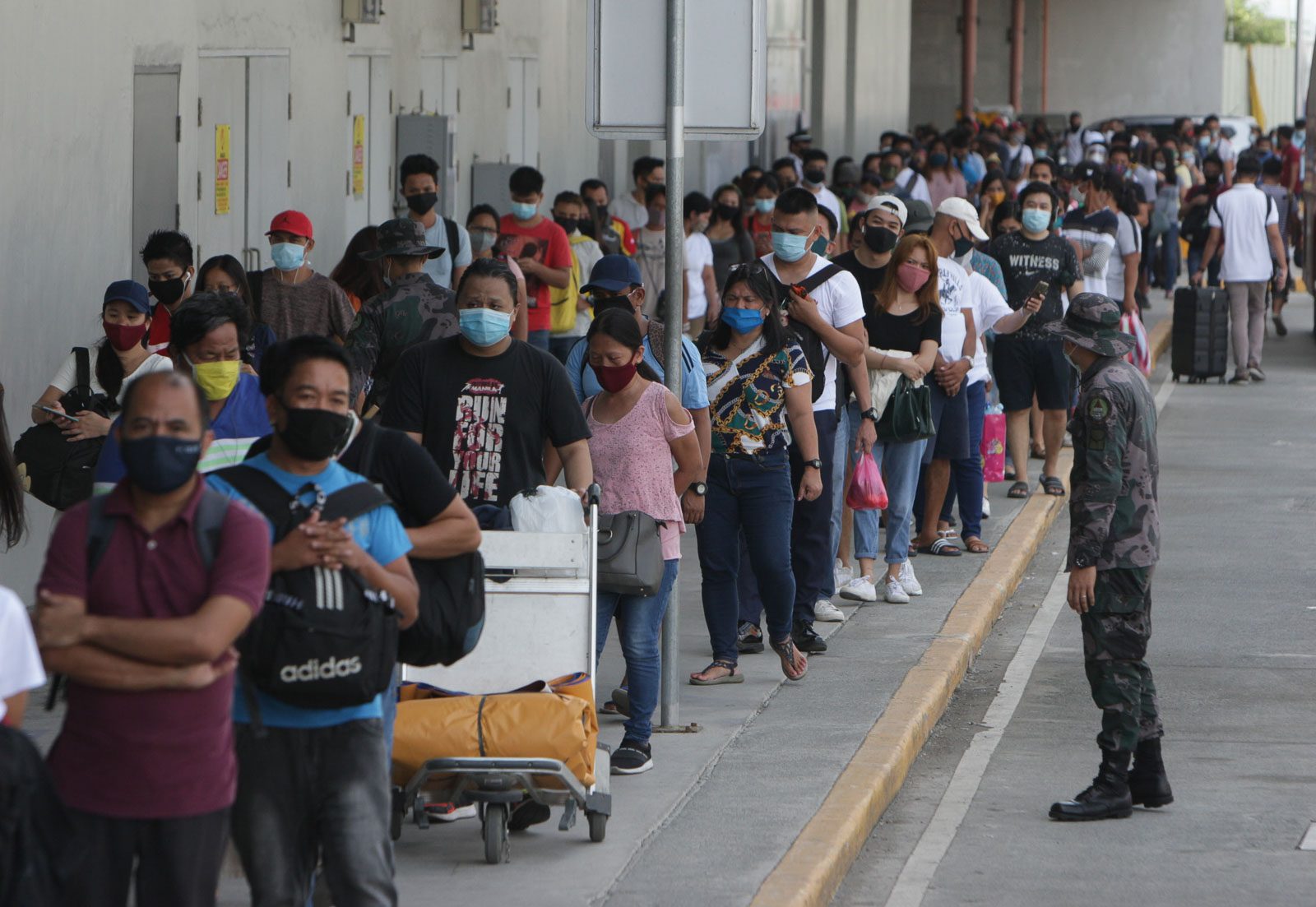 WAITING. Police remind Cavite commuters entering Metro Manila to practice physical distancing. Photo by Ben Nabong/Rappler 