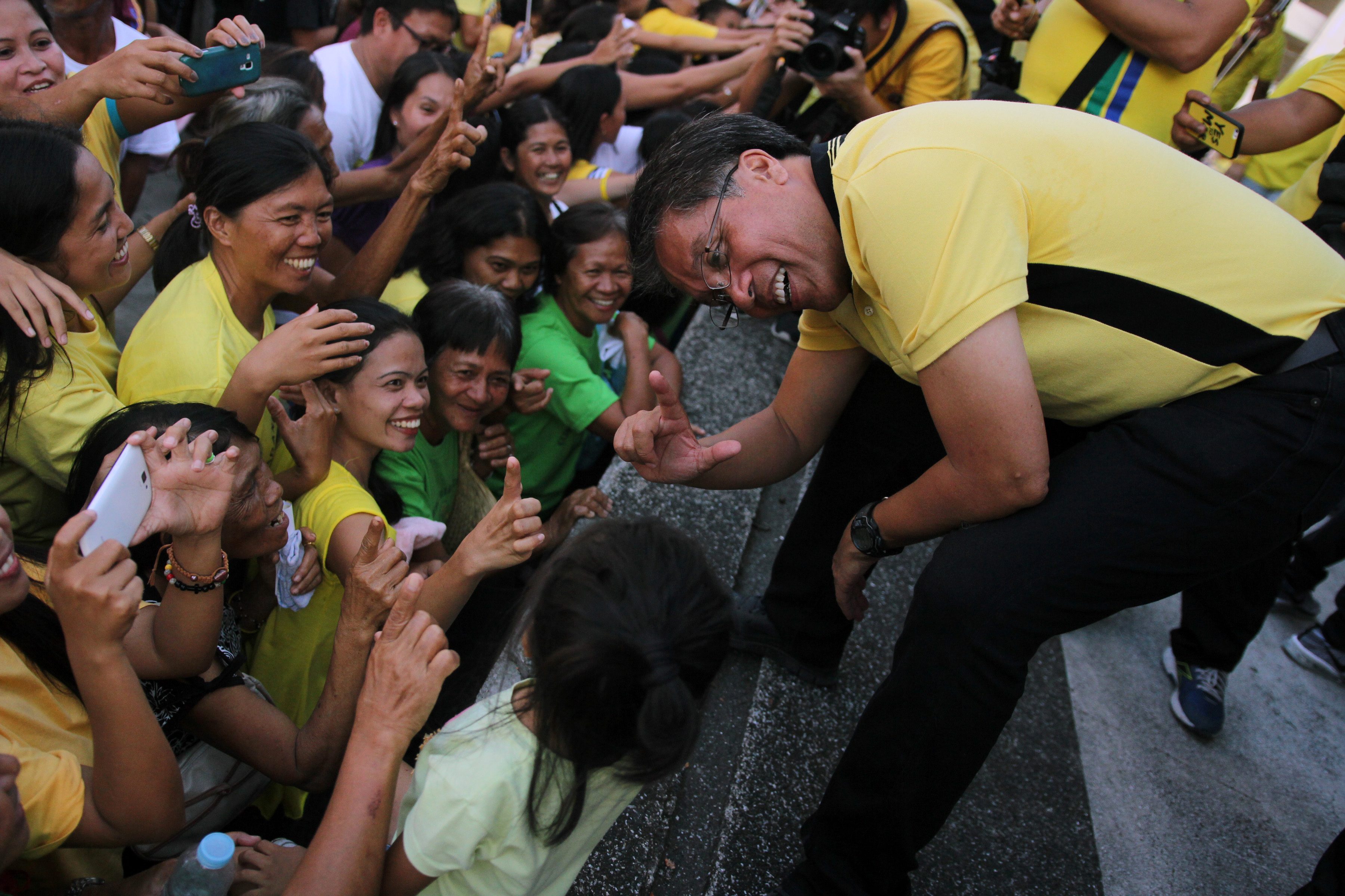 CAMPAIGN LESSONS. Mar Roxas teaches a young Bicolano how to flash the LP's signature 'L' sign.  
