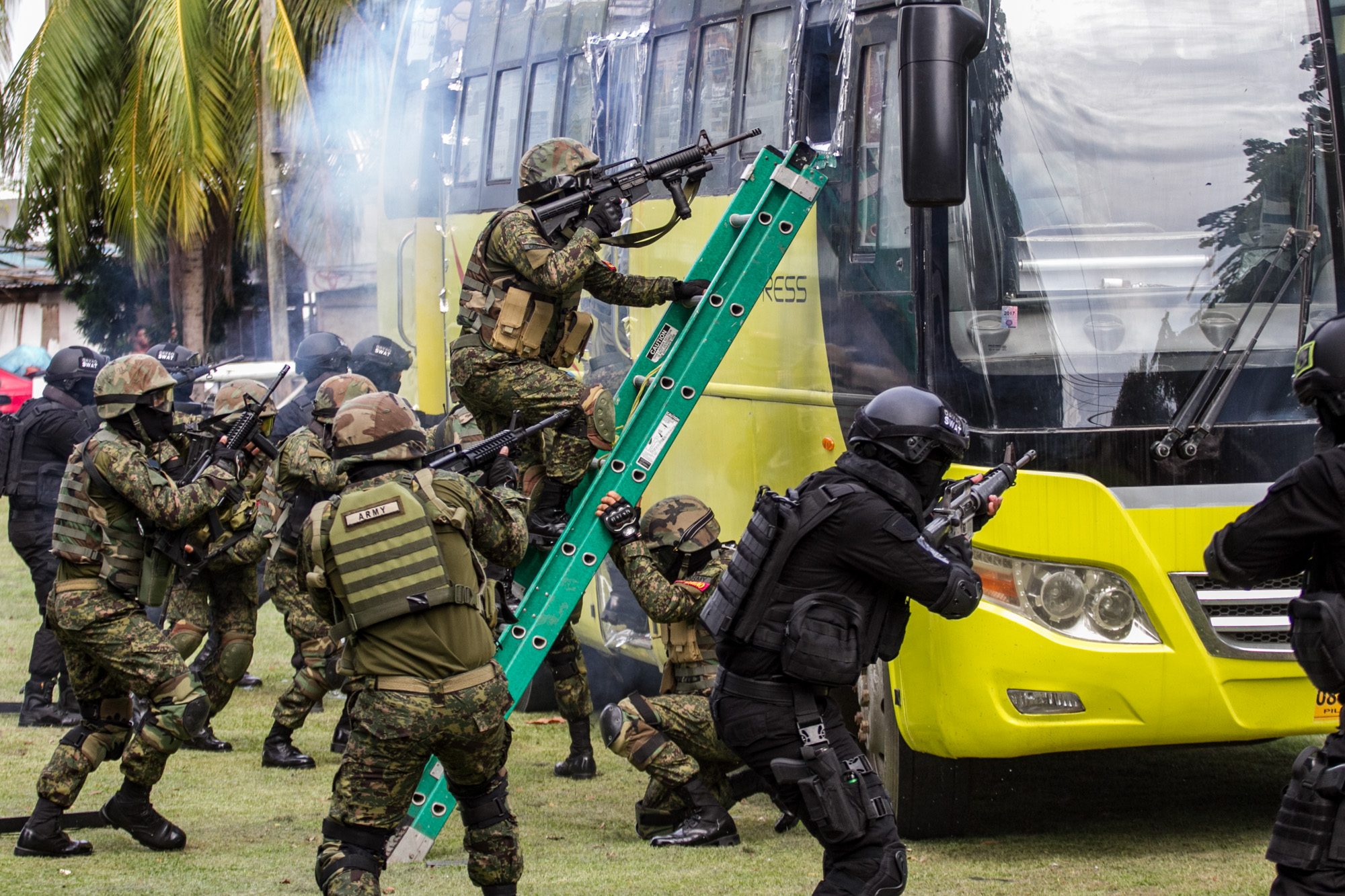 DRILL. A SWAT team maneuvers to retake a bus in a hostage situation.  
