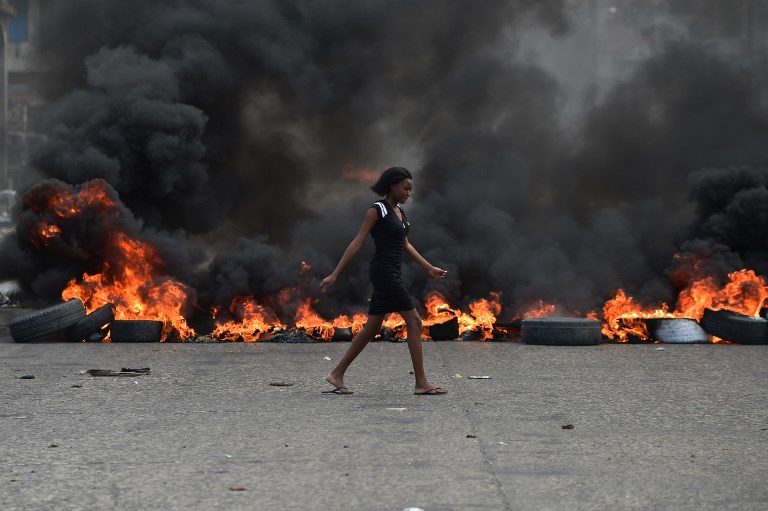 HAITI BURNING. A woman walks past tire barricades set ablaze by demonstrators on the fourth day of protests in Port-au-Prince, February 10, 2019, against Haitian President Jovenel Moise and misue of Petrocaribe fund. Photo by Hector Retamal/AFP  