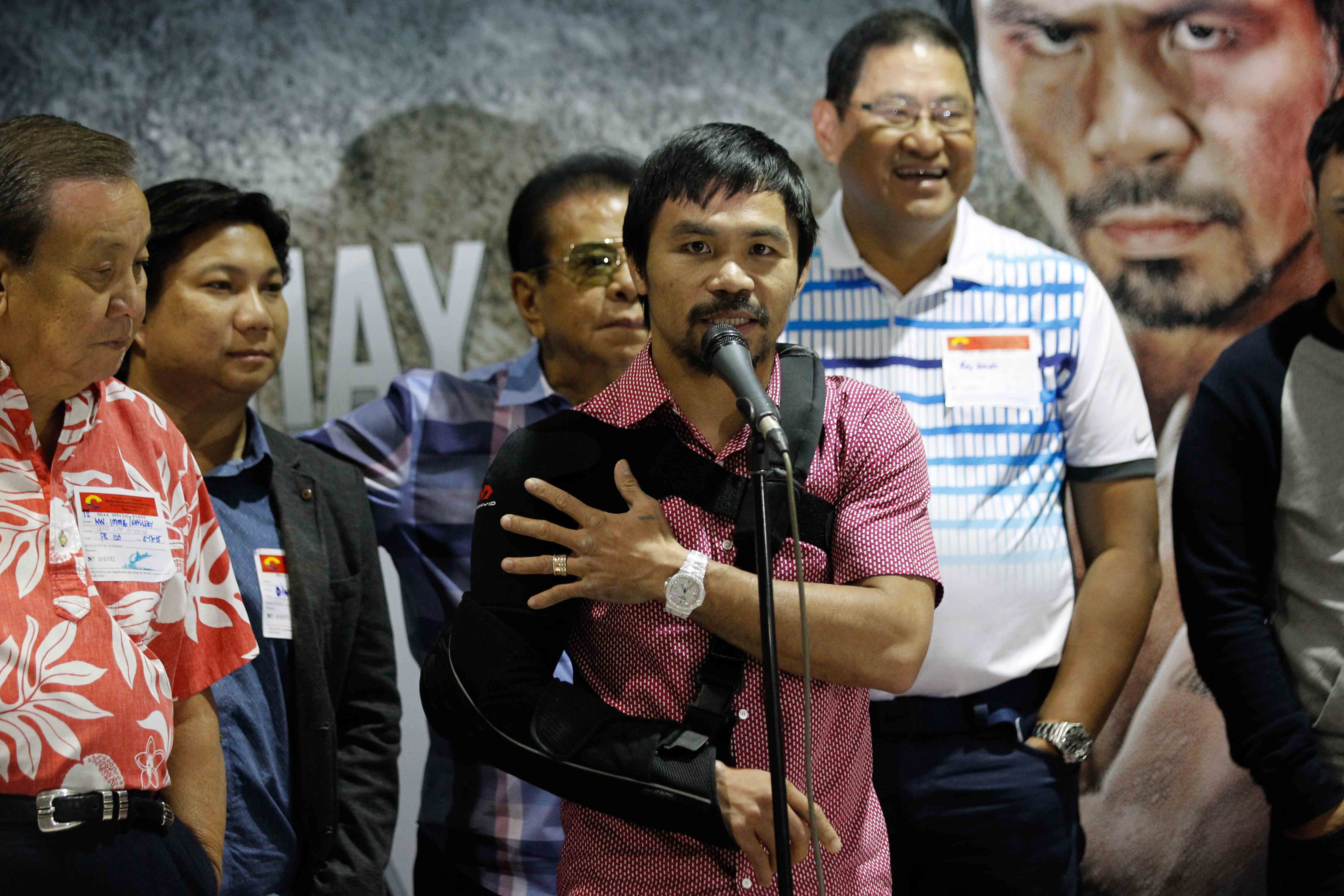 Manny Pacquiao clutches his right arm as he addresses reporters at NAIA Terminal II. Photo by Czeasar Dancel/Rappler 