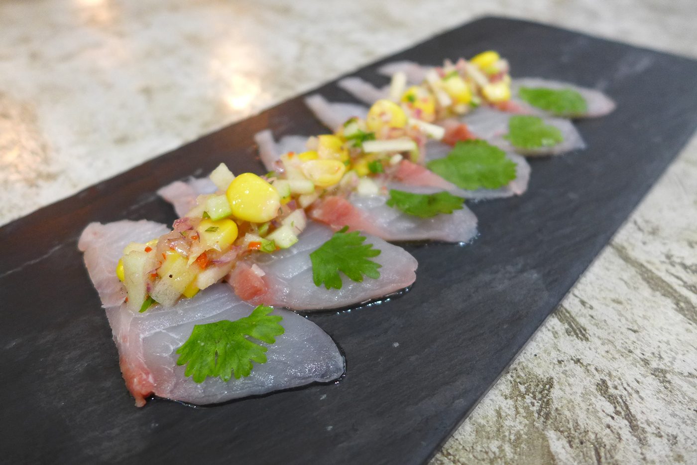 SASHIMI REDUX. Delicately slivers of white fish topped with a medley of cilantro, chili, onion, corn and green apple.
 