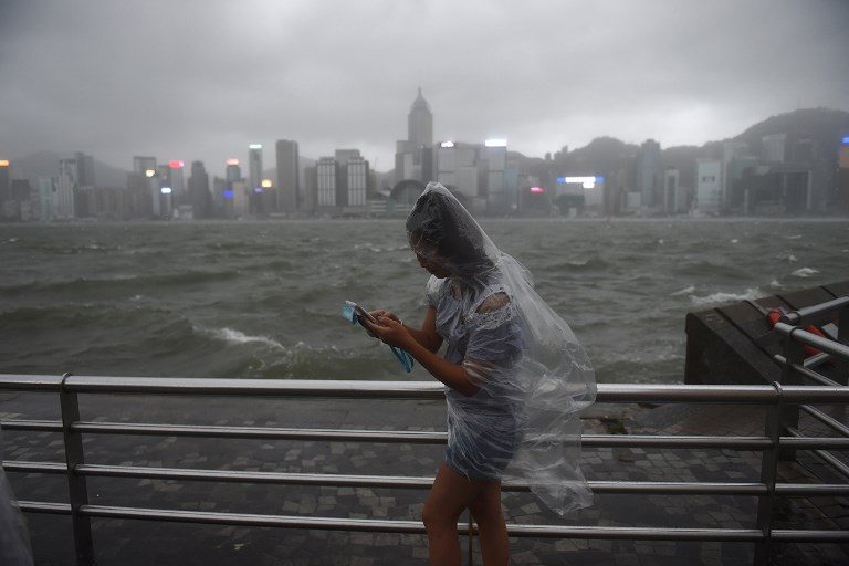 SIGNAL NO. 10. A woman uses her phone along Victoria Harbour amid heavy winds and rain brought by Typhoon Hato in Hong Kong on August 23, 2017. Photo by Anthony Wallace/AFP   