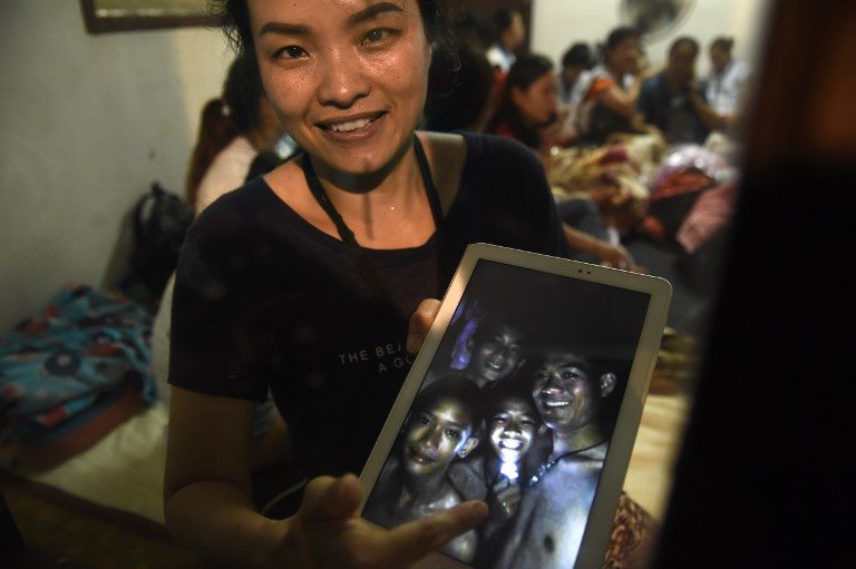 'FOUND SAFE.' A family member shows a picture of 4 of the 12 missing boys near the Tham Luang cave at the Khun Nam Nang Non Forest Park in Mae Sai on July 2, 2018. Photo by Lillian Suwanrumpha/AFP  