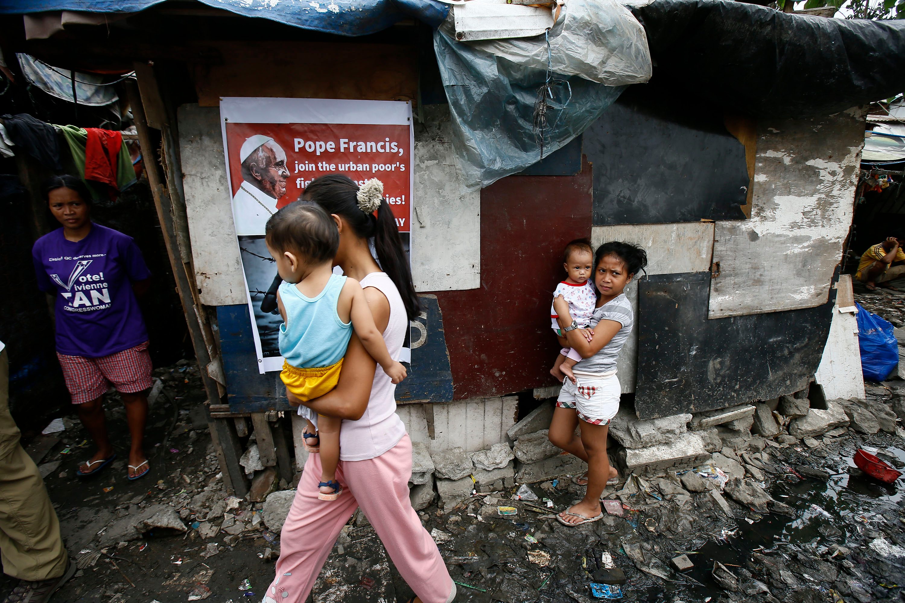 THE COUNTRY'S POOR. Filipino food scavengers walk past a portrait of Pope Francis at the Payatas dump site ahead of Pope Francis' visit in Quezon City, eastern Manila, Philippines, January 13, 2015. Photo by Dennis Sabangan/EPA 