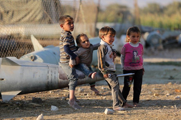 CHILDREN OF WAR. Syrian children play as they sit on the tip of an abandoned missile at the Ash'ari camp for the displaced in the rebel-held Ghouta area outside Damascus on October 25, 2017. Photo by Amer Almohibany/AFP  