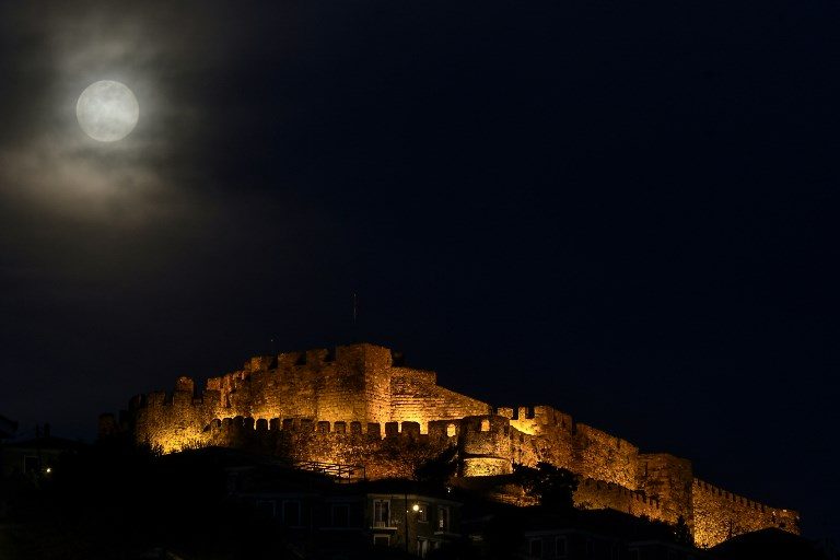 GREECE. A full moon rises next to the ancient castle of Mithymna Molyvos on the Greek island of Lesbos on March 20, 2019. Photo by Aris Messinis/AFP  