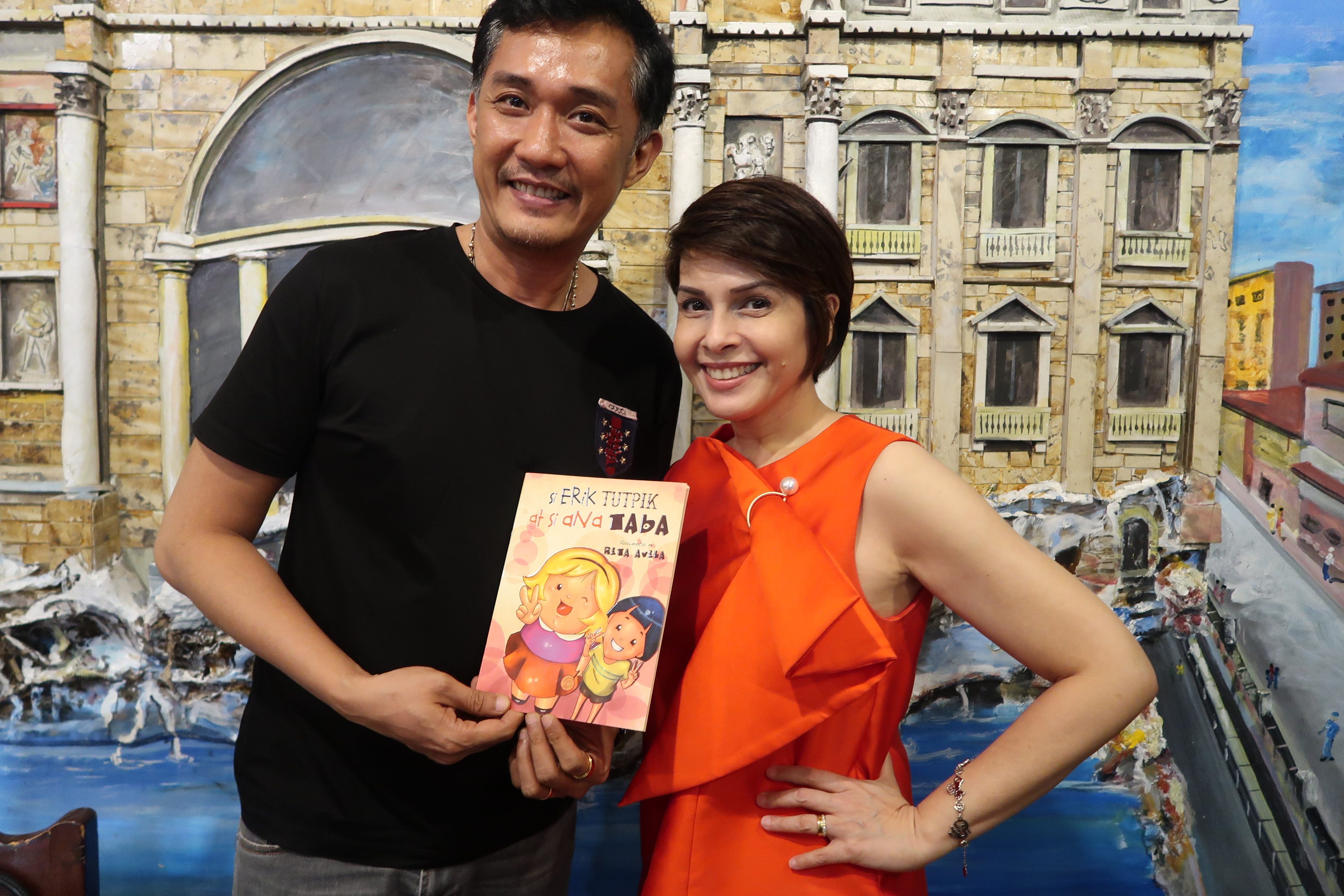 Rita and director FM Reyes holds her first children’s book, 'Si Erik Tutpik at Ana Taba,' a story loosely inspired by their childhood. 