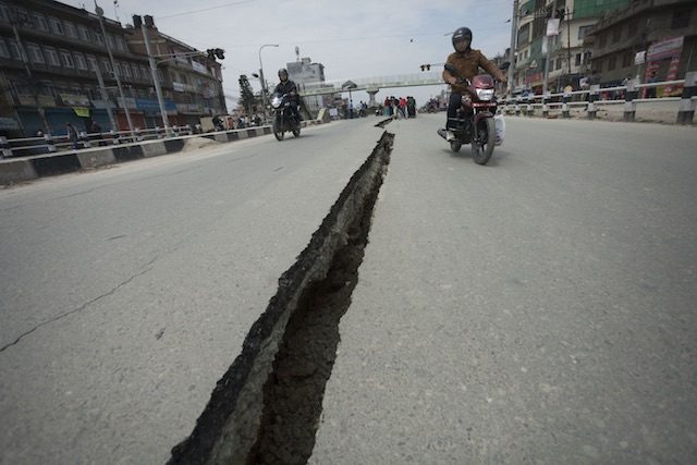 CRACKED OPEN. Motorcyclists use both sides of a wide crack in the Koteshwor-Suryabinayak Highway caused by the earthquake in the Bhaktapur area near Kathmandu, Nepal on 26 April, 2015 – twenty four hours after a devastating quake which so far has taken the lives of at least 2,400. Hemanta Shrestha/EPA 