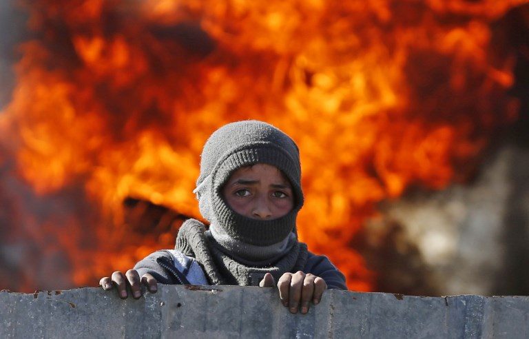 BORDER WAR. A masked Palestinian stands in front of flames during clashes with Israeli soldiers at the entrance of the northern village of Qusra in the occupied West Bank near Nablus on December 4, 2017. Photo by Abbas Momani/AFP   