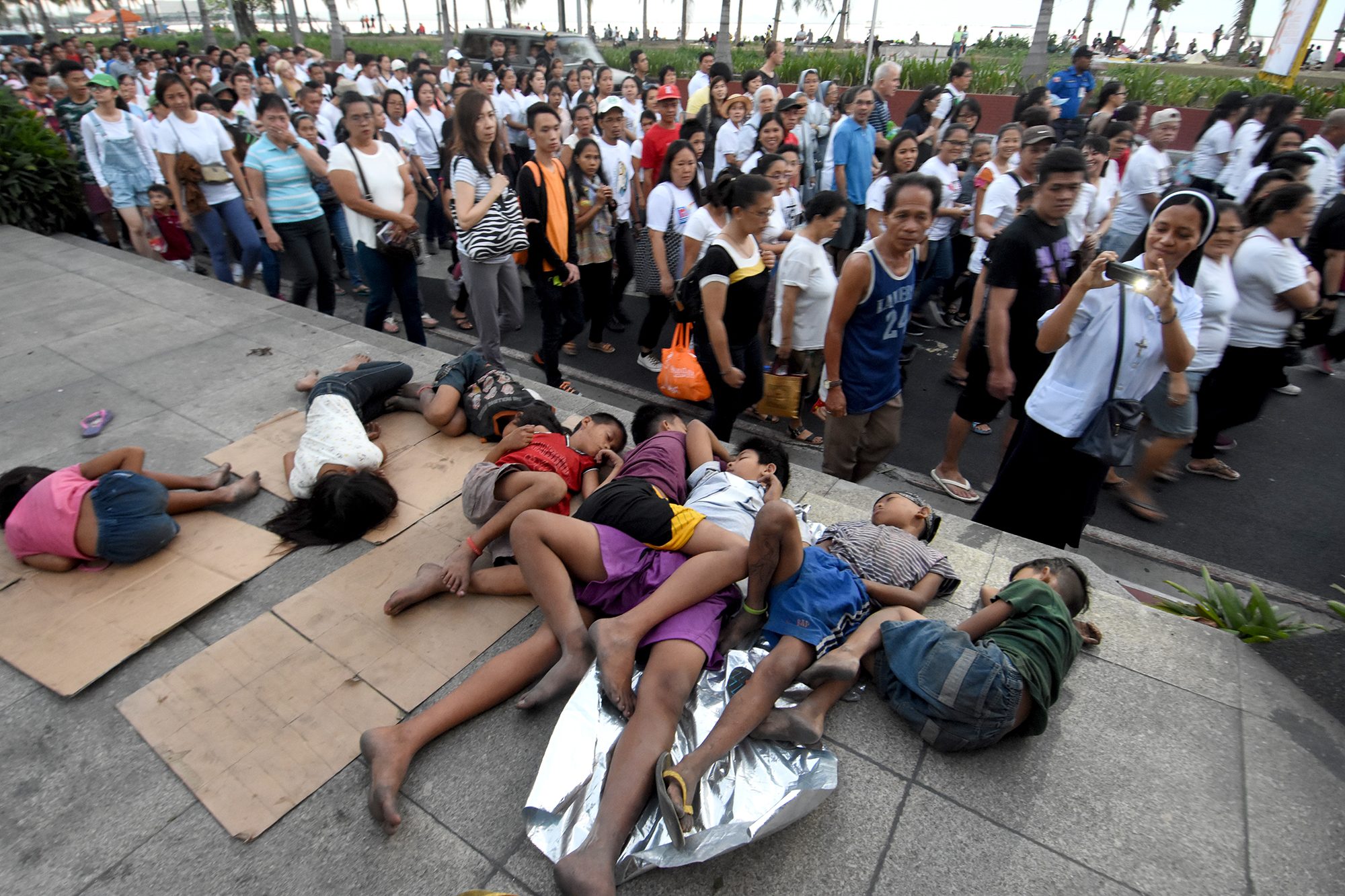 SNAPSHOT. A participant of the Good Friday, April 14, 'Walk for Life' procession takes a photo of the homeless along Roxas Boulevard in Manila. Photo by Angie de Silva/Rappler   