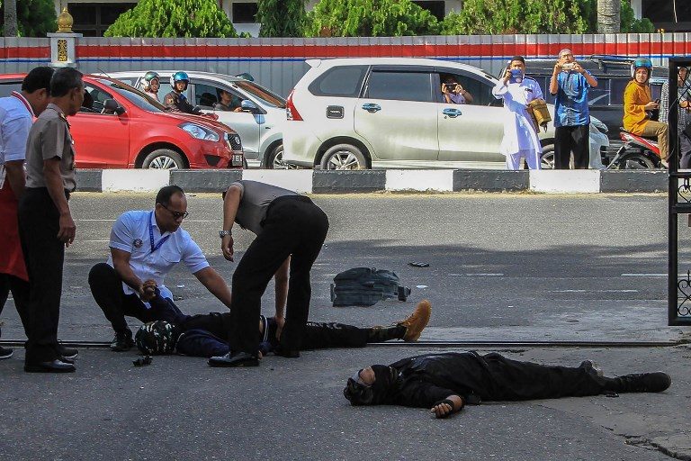 FOILED ATTACK. Onlookers take pictures as police examine the bodies of two people who launched an attack on the police headquarters in Pekanbaru on May 16, 2018. AFP Photo  